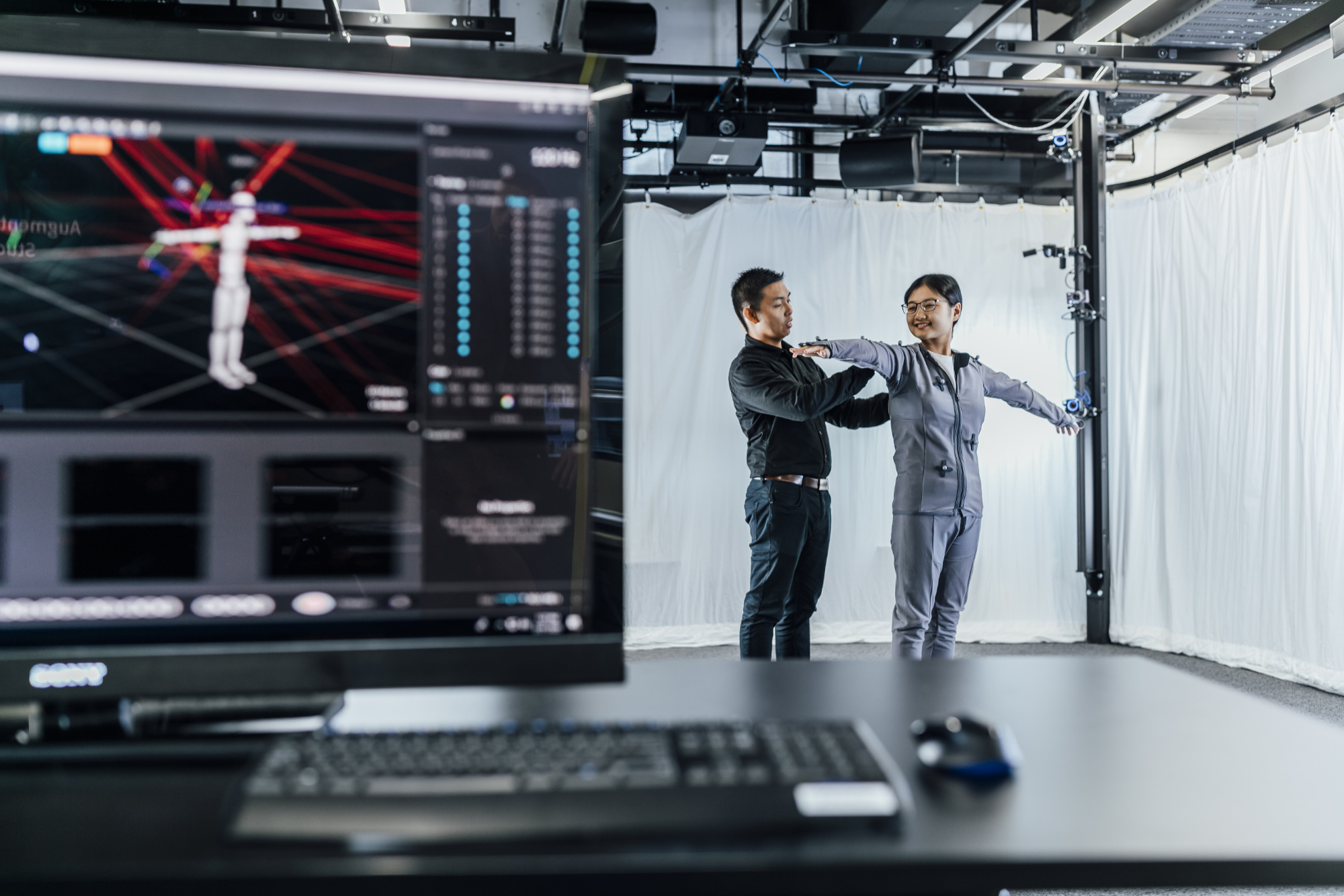 image of two individuals in a computing lab with a computer monitor showing measurements being taken from the people