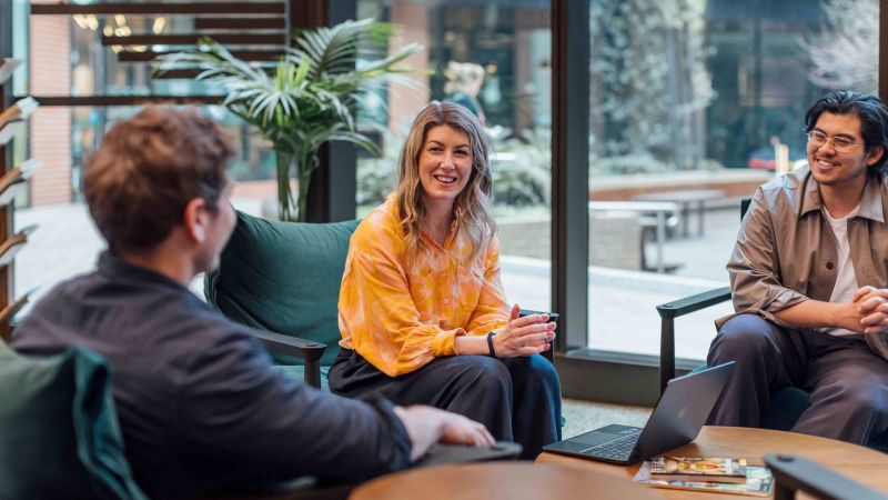 A group of three people sitting around a coffee table