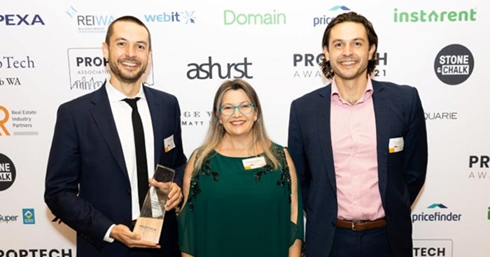 Exergenics cofounders standing in front of a sponsor branded wall at Proptech Association of Australia award dinner