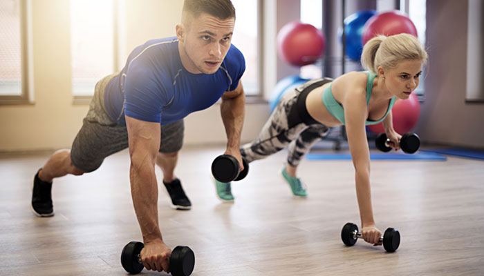 A man and a women doing push-ups with hand weights